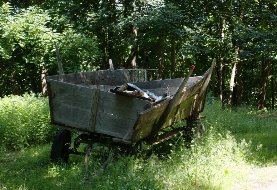 A dilapidated wooden wagon with one wheel modern and one missing