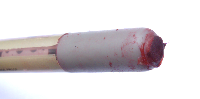 The end of a pen plugged with a piece of paper, all soaked with red.