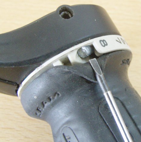 The shifer is one piece again. A screw driver lifts a rubber flap that's part of the handle to reveal a cute little metal head of the cable tucked away inside the white piece.